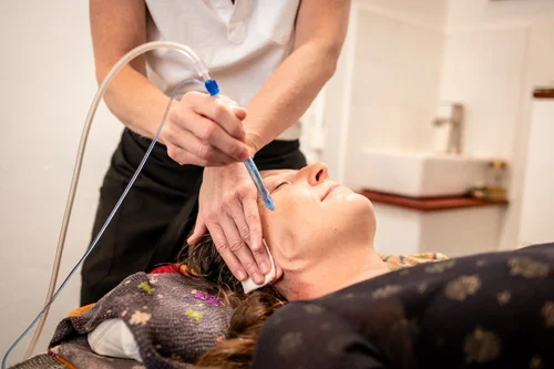 The JetPeel handpiece delivering cold hydration along a reclining client's cheek